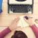 Girl typing on the old typewriter.